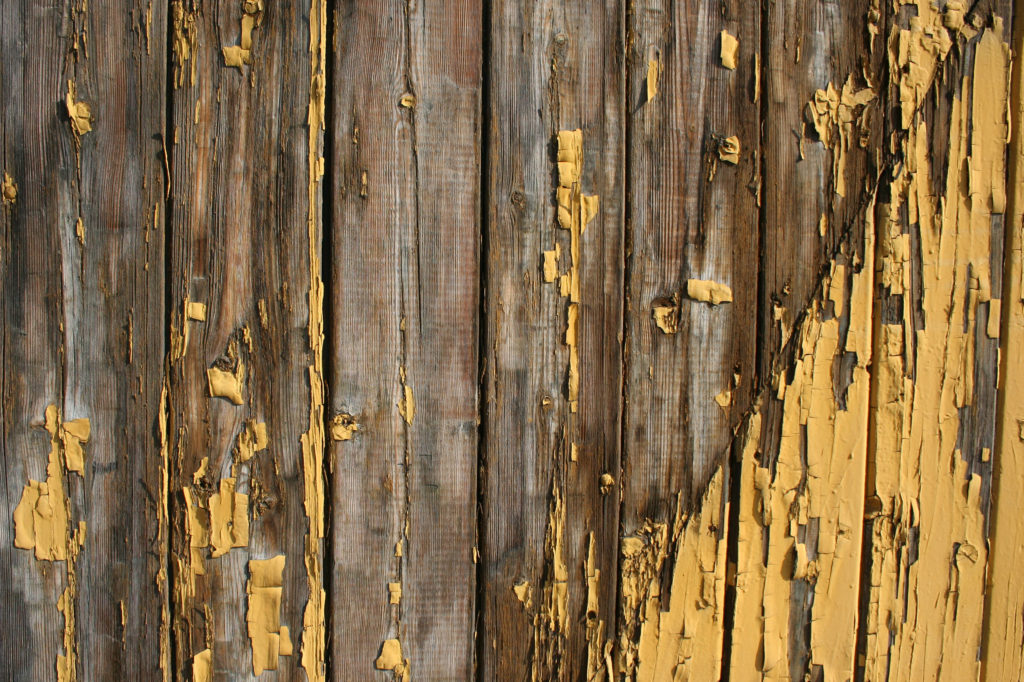 Old yellow paint peeling on a wood deck