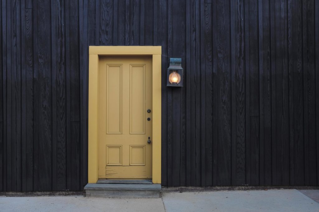 front door painted in yellow with light next to it