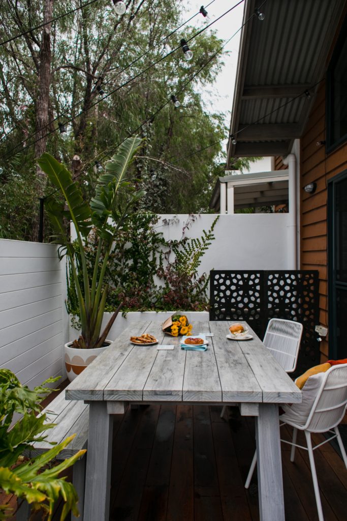 table painted gray and bench on patio with plants