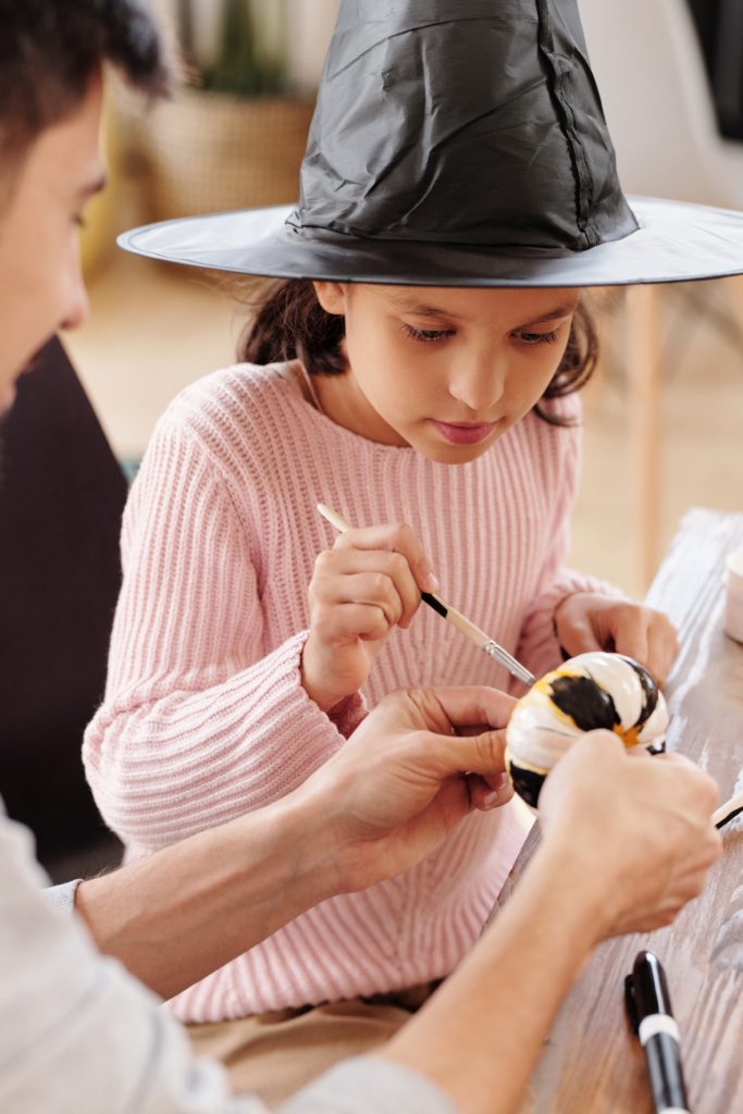 Girl painting pumpkin in witch hat