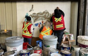 Volunteers in safety vests painting the community mural together.
