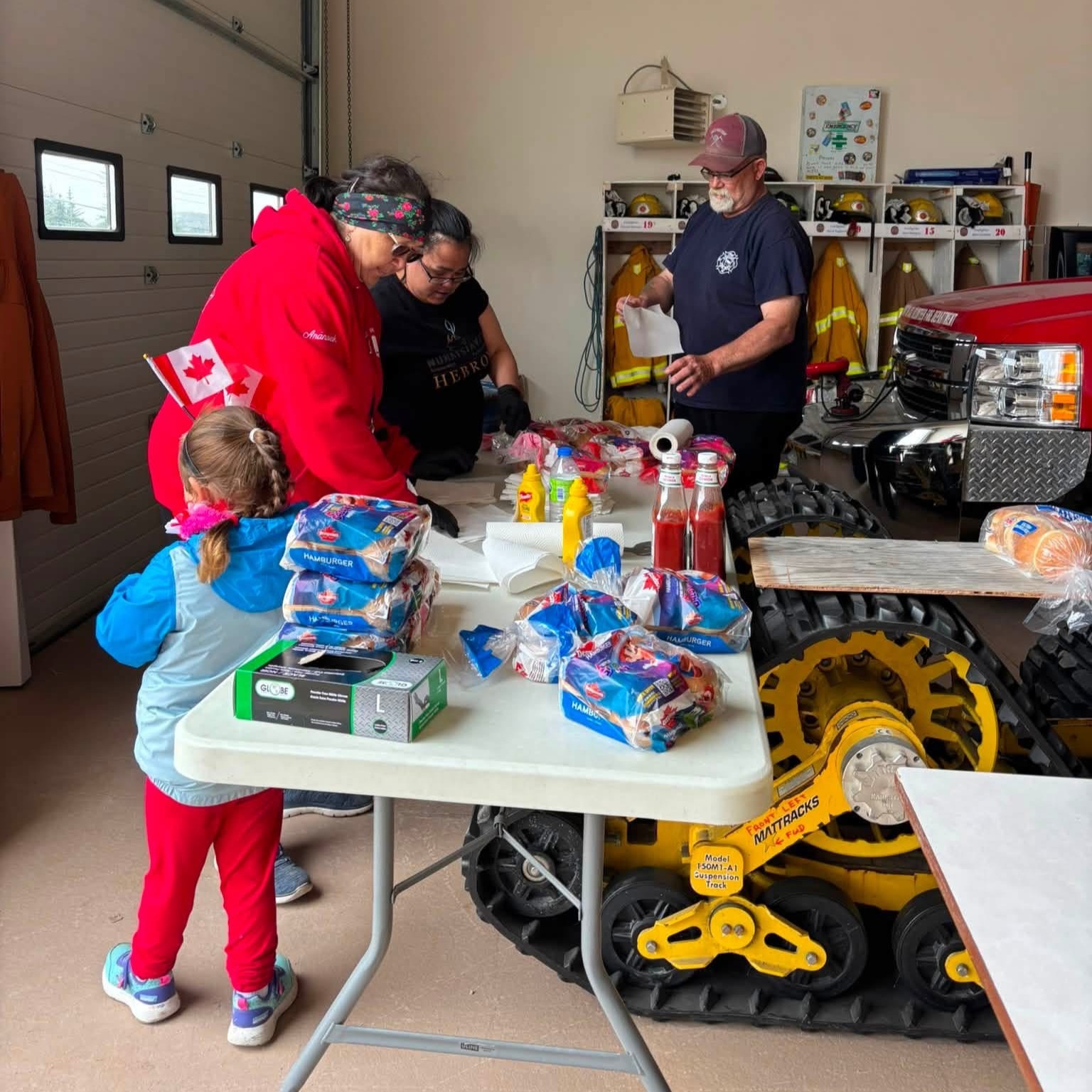 Volunteers gather around a table of food and supplies inside the Hopedale fire hall